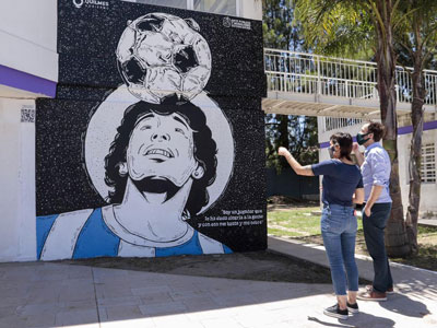 Mayra Mendoza junto al mural de Maradona en el Polideportivo Municipal.